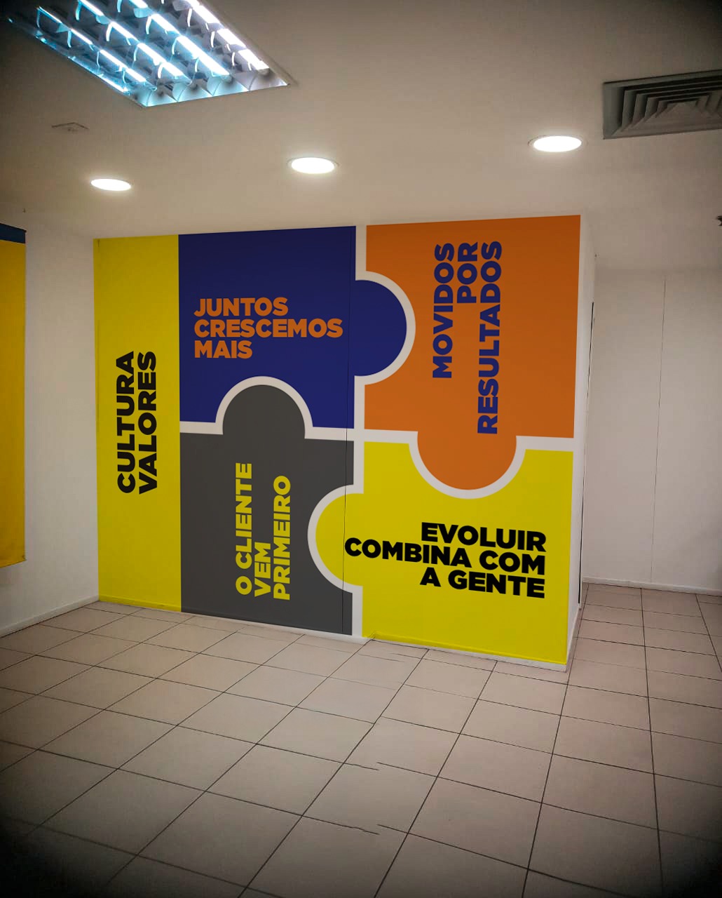 Painel decorativo cobrindo uma parede inteira, com recortes em cores e tipografia grande